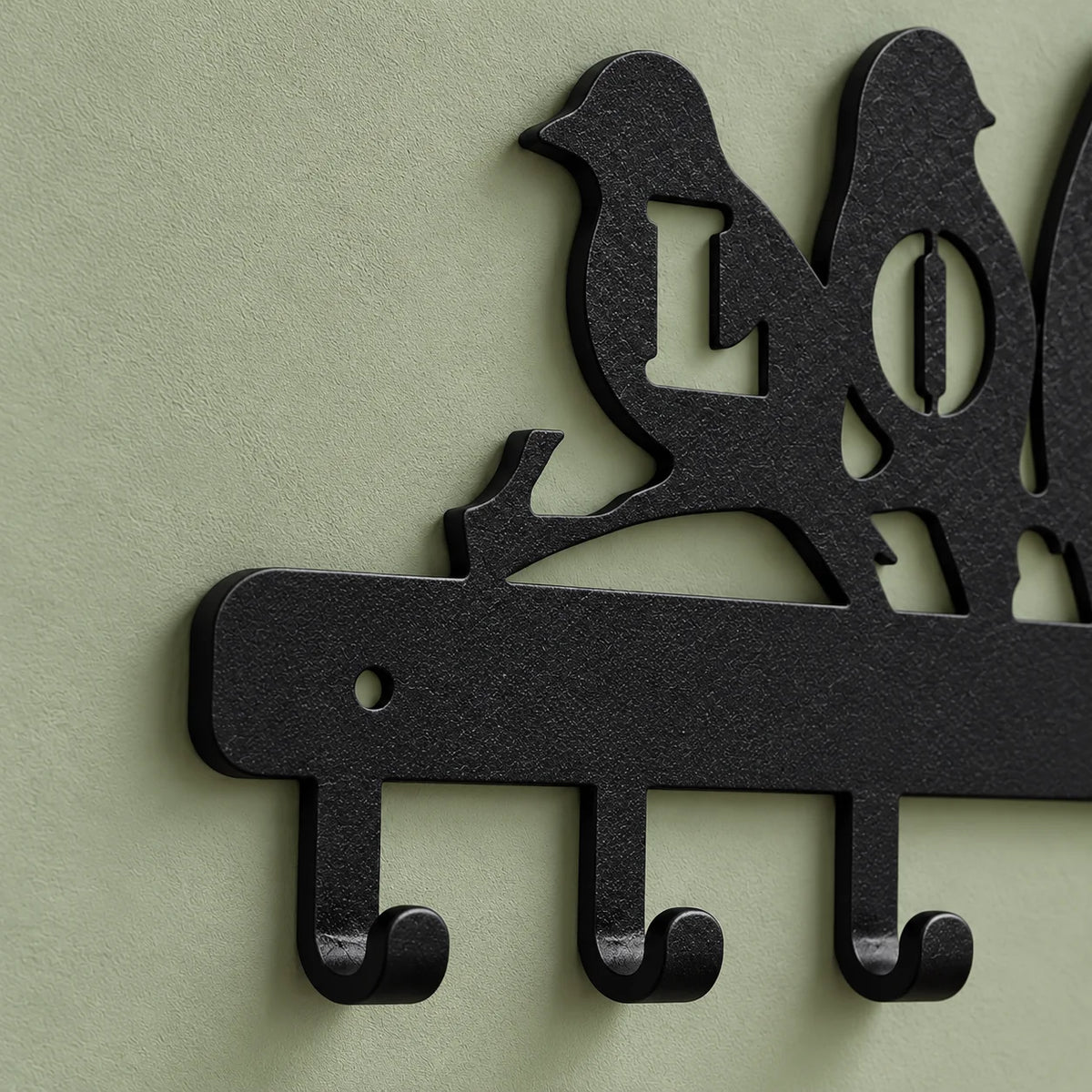 Détail des crochets et de la fixation gauche du porte-manteau LOVE noir sur fond vert