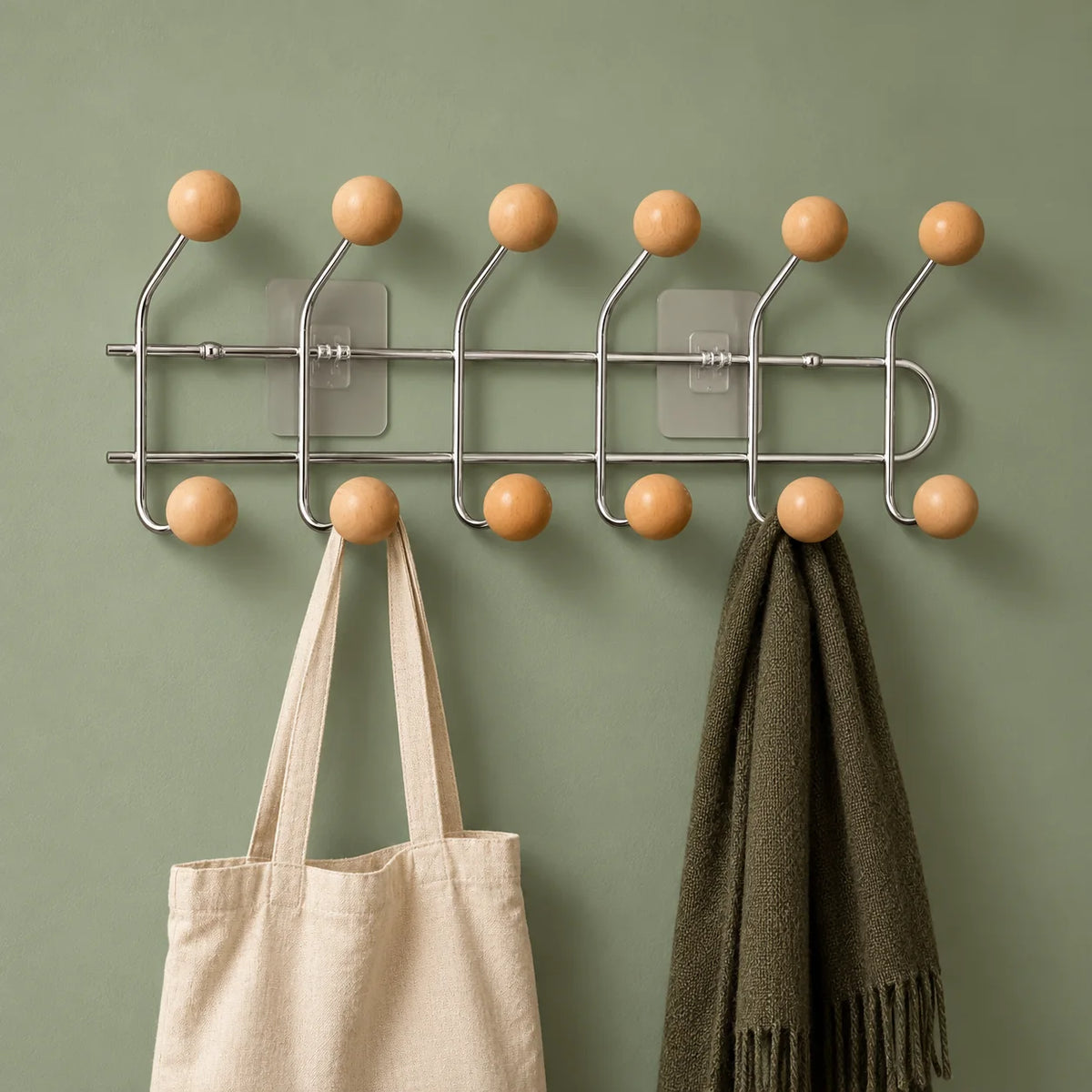 Porte-manteau chromé à boules bois avec sac et écharpe sur fond vert sauge
