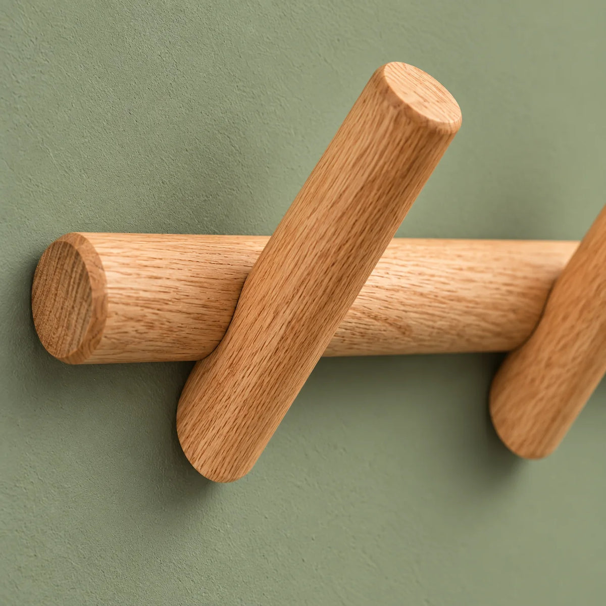 Détail du grain du bois et de l'assemblage d'une patère sur fond vert sauge