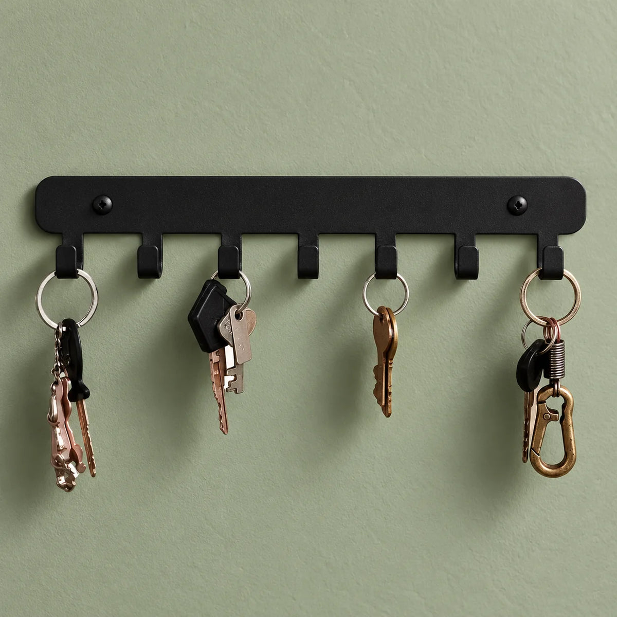 Détail des sept crochets noirs avec quatre trousseaux de clés sur fond vert