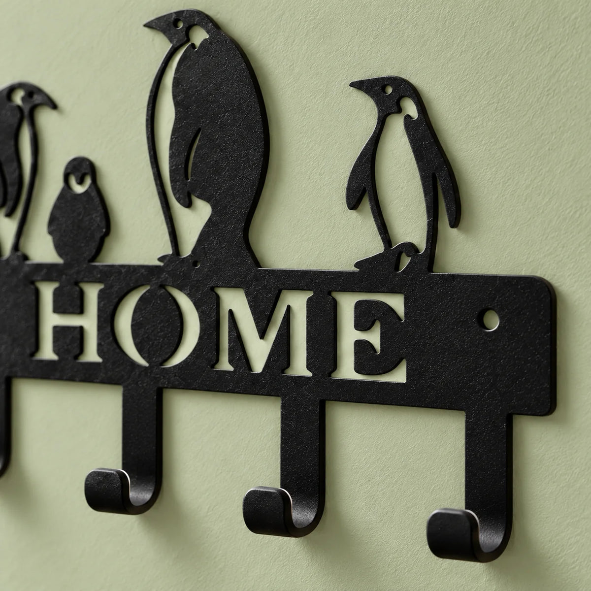 Détail du lettrage HOME, des pingouins et des crochets noirs sur fond vert