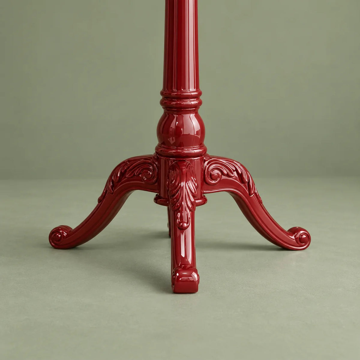 Détail du piètement à trois branches du porte-manteau rouge sur fond vert