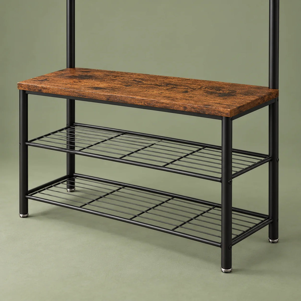 Banc en bois brun foncé et deux grilles à chaussures noires sur fond vert