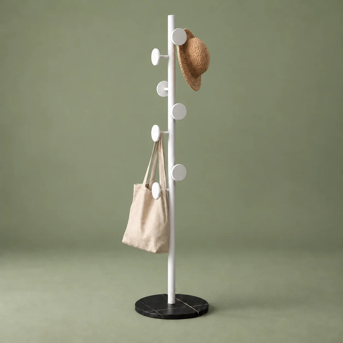 Porte-manteau champignon blanc et noir avec chapeau et sac en toile sur fond vert sauge
