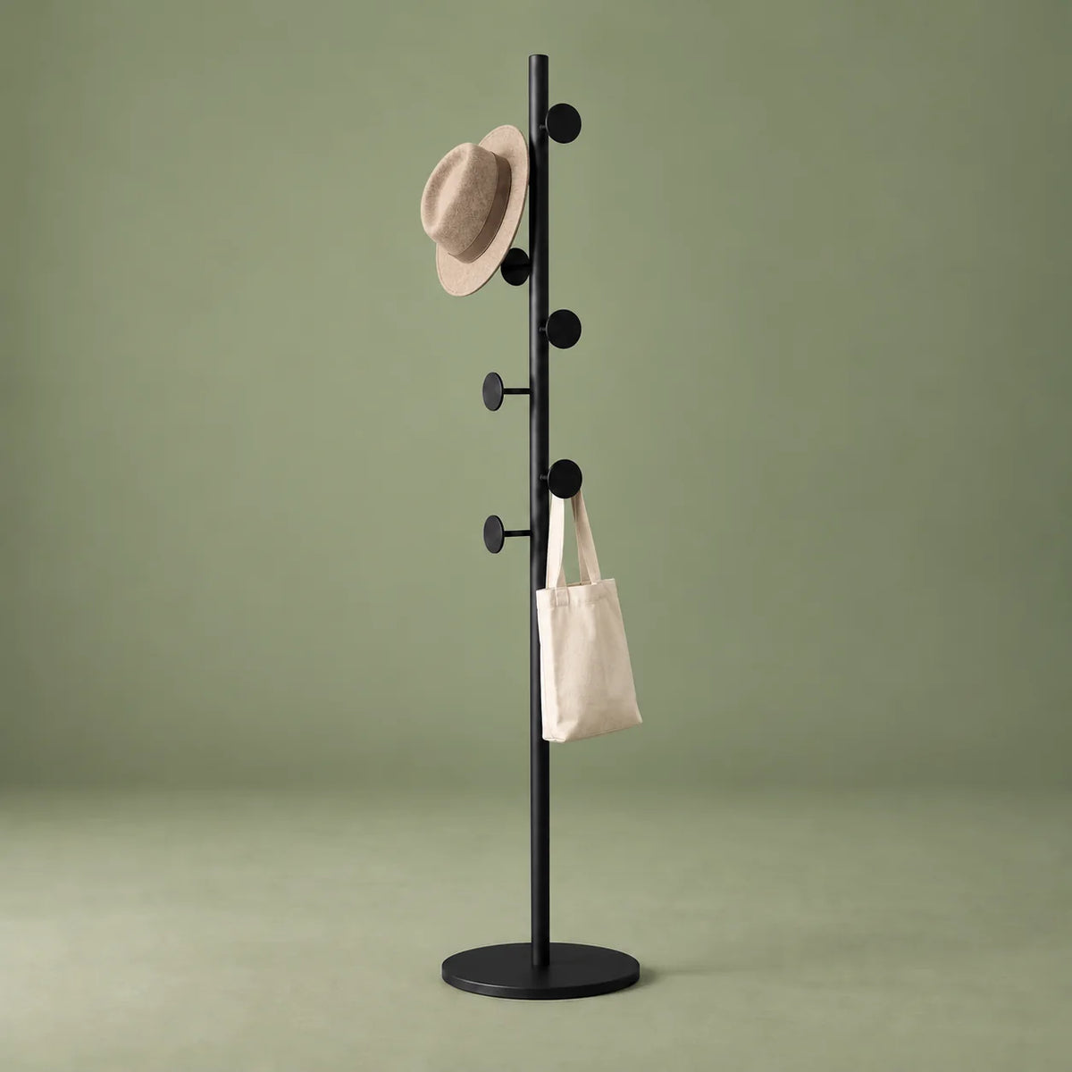 Porte-manteau champignon noir avec chapeau et sac en toile sur fond vert sauge