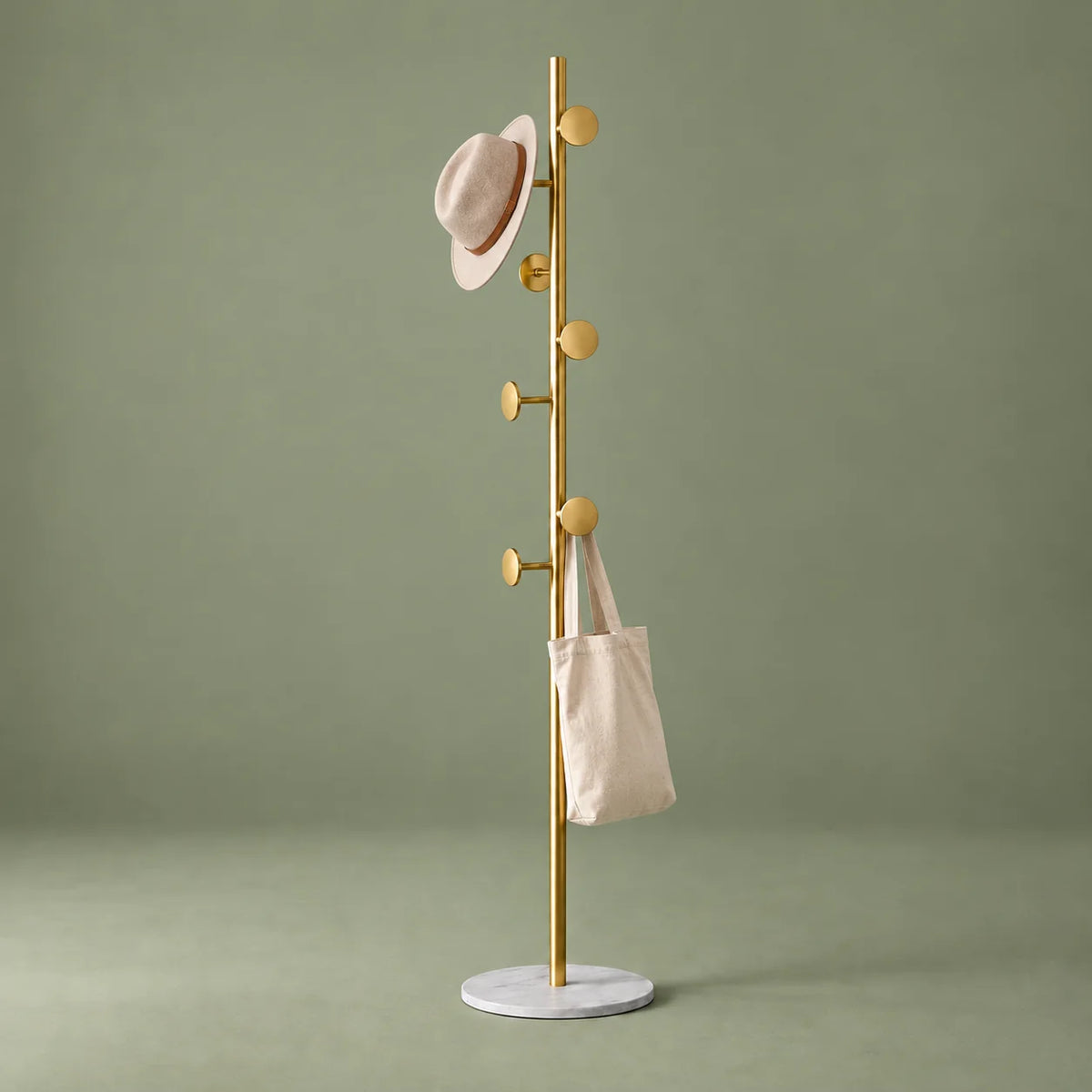 Porte-manteau champignon doré et blanc avec chapeau et sac sur fond vert sauge