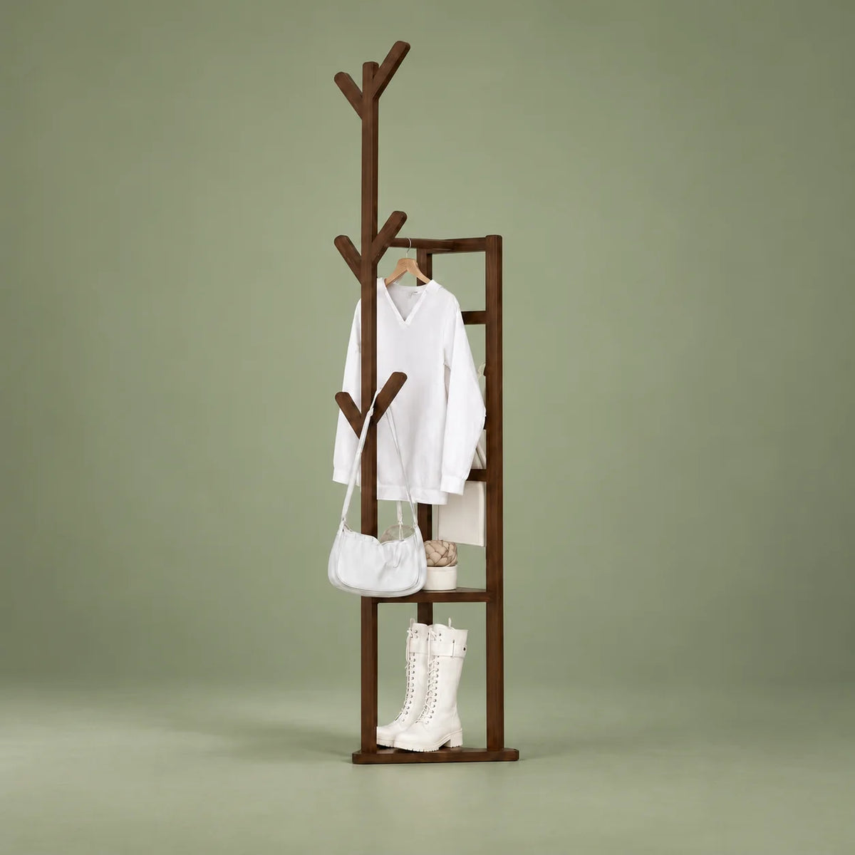 Vue entière du porte-manteau multifonction en bois foncé sur fond vert sauge