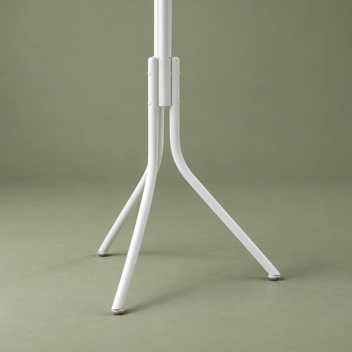 Détail du piètement incliné du porte-manteau perroquet blanc sur fond vert