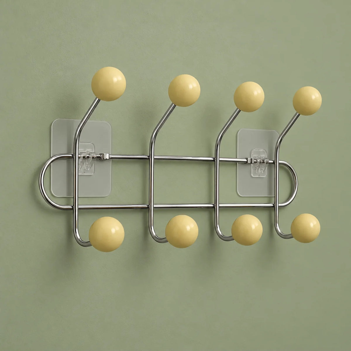 Vue oblique des quatre bras chromés et huit boules bois jaune crème sur fond vert