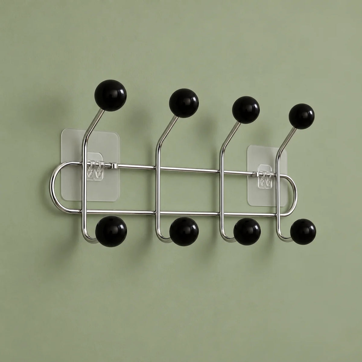 Vue oblique des quatre bras chromés et huit boules noires sur fond vert sauge