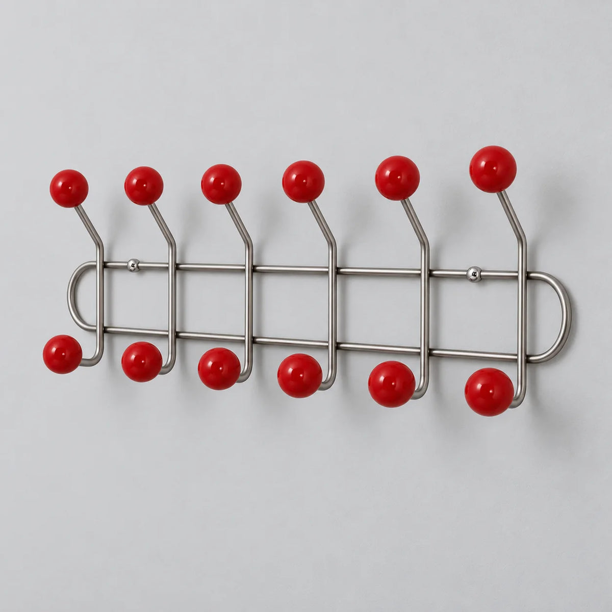 Vue oblique du porte-manteau mural à six doubles crochets rouges montrant leur avancée
