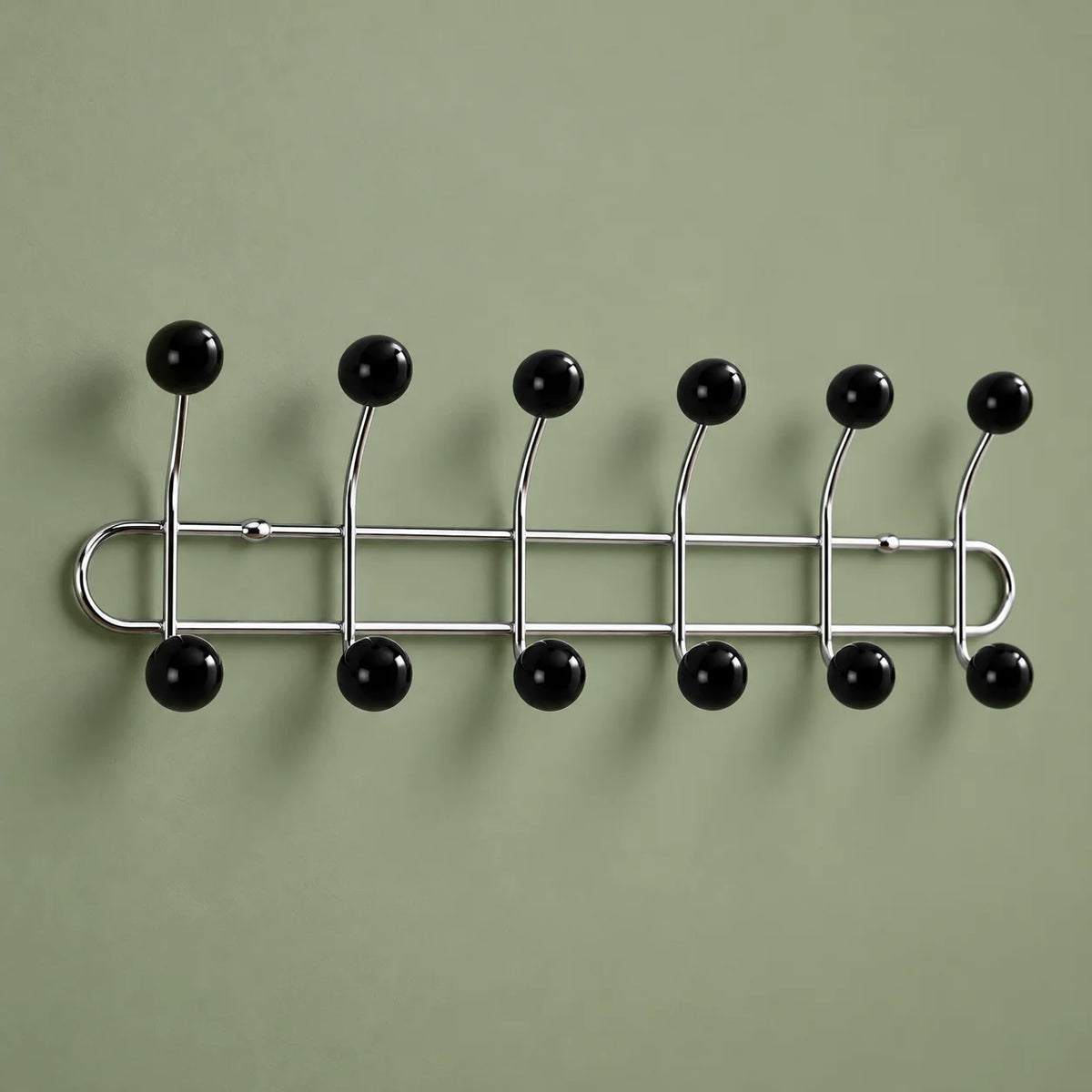 Vue oblique des six bras chromés et douze boules noires sur fond vert sauge
