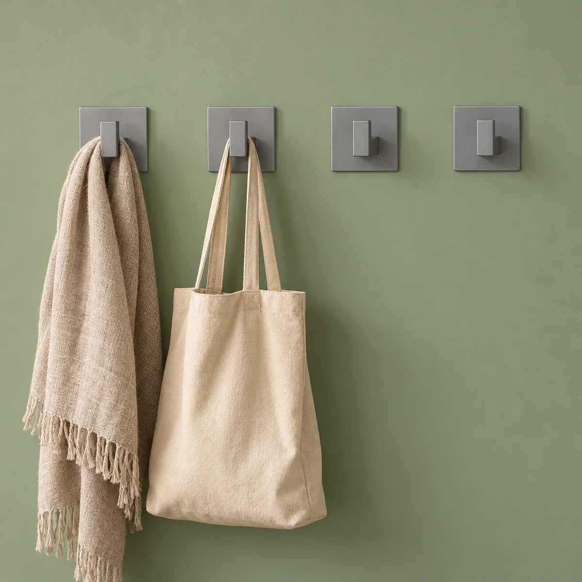 Quatre patères Original grises avec écharpe et sac sur mur vert sauge