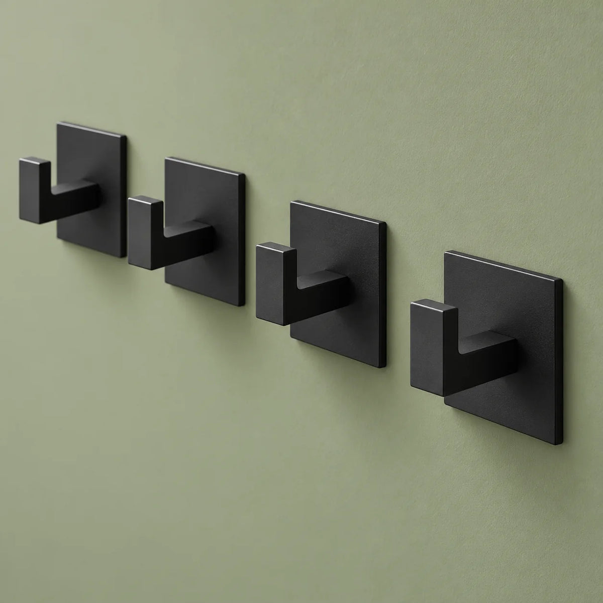 Quatre patères Original noires vues de trois quarts sur fond vert sauge
