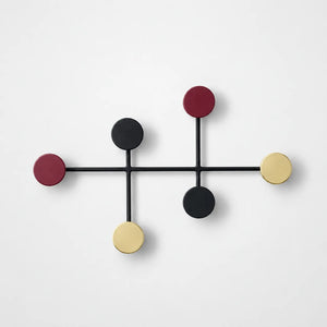 Porte manteau mural rond colore avec six disques bordeaux noir et laiton, fond studio gris clair