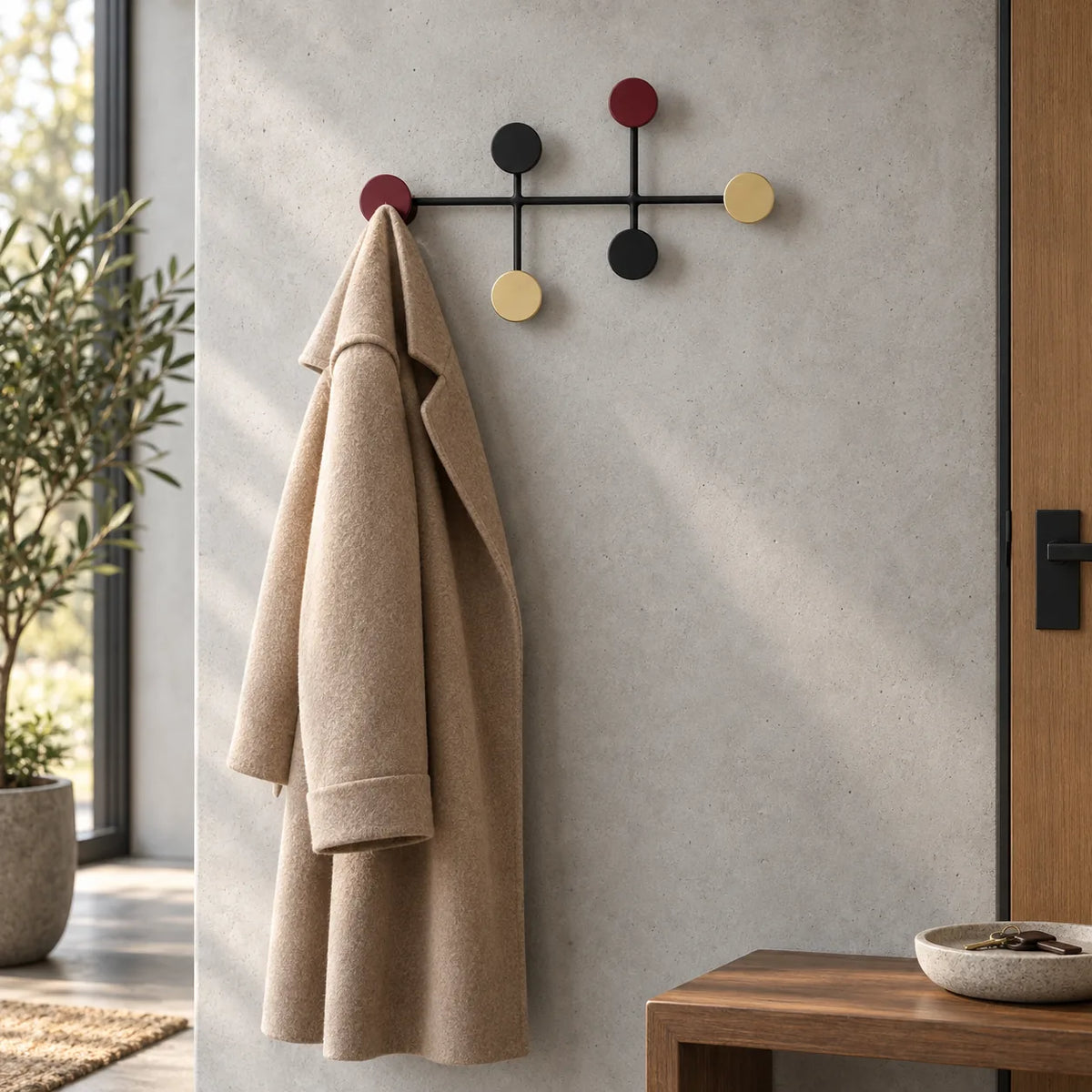 Porte manteau mural colore fixe sur un mur en beton cire avec un manteau en laine beige