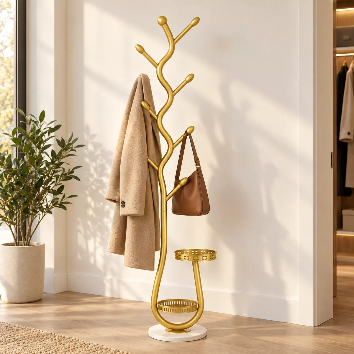 Porte manteau sur pied doré dans une entrée claire avec manteau et sac en cuir suspendus